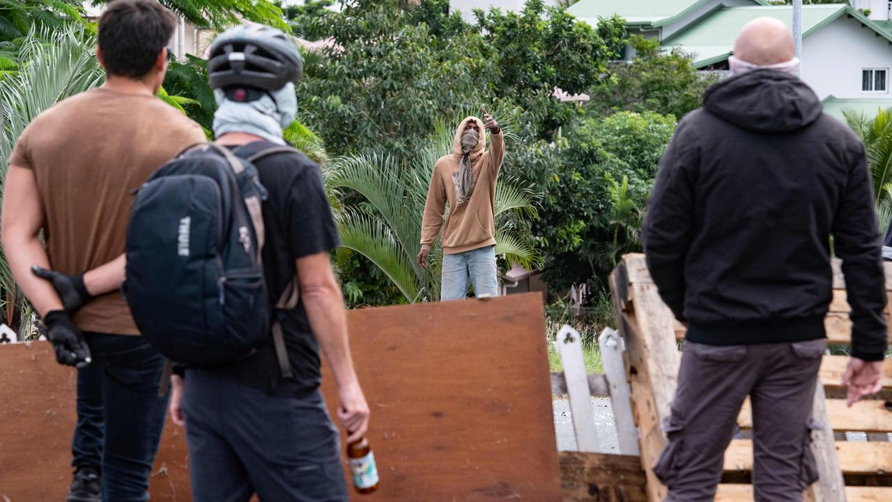 Masked residents watch an activist at the entrance to Tuband, in the Motor Pool district of Noumea on May 15, 2024, amid protests linked to a debate on a constitutional bill aimed at enlarging the electorate for upcoming elections of the overseas French territory of New Caledonia. One person was killed, hundreds more were injured, shops were looted and public buildings torched during a second night of rioting in New Caledonia, authorities said Wednesday, as anger over constitutional reforms from Paris boiled over. (Photo by Delphine Mayeur / AFP)
