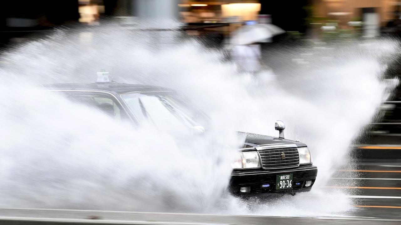 A taxi speeds through water covering a road in the Aoyama district of Tokyo. Picture: AFP