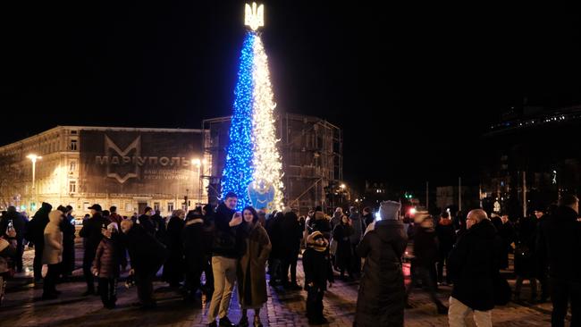 People gather near a Christmas tree decorated in the colours of the Ukrainian flag in a Kyiv square on Sunday. Picture: Getty Images