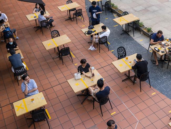 Customers sit at socially distanced tables outside a restaurant in Singapore, on Monday, June 21, 2021. Singapore has decided to scale down its reopening plans amid dozens of new cases over the last week, even as some countries with similarly high rates of vaccination allow a resumption of social activities and freer travel. Photographer: Wei Leng Tay/Bloomberg via Getty Images