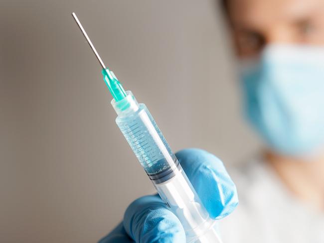 doctor with a medical face mask and syringe. vaccination concept