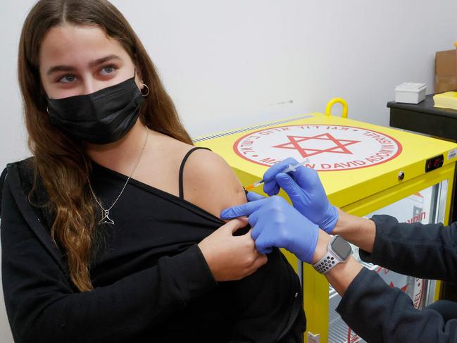 An Israeli Magen David Adom medical administers a dose of the Pfizer-BioNtech vaccine against the coronavirus to a young Woman, in the Israeli town of Ramat Gan near Tel Aviv, on December 23, 2021. - Israelis over the age of 60 and medical teams will be eligible for a fouth Covid vaccination, following the recommendation of an expert panelas the Jewish state struggles to contain the spread of the Omicron variant, imposing travel and other restrictions while avoiding a domestic lockdown. (Photo by JACK GUEZ / AFP)