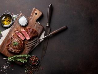 Grilled ribeye beef steak, herbs and spices. Top view with copy space for your text