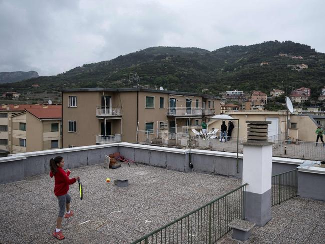 Childen play tennis on the rooftops of their house in northwestern Italy. Picture: AFP.