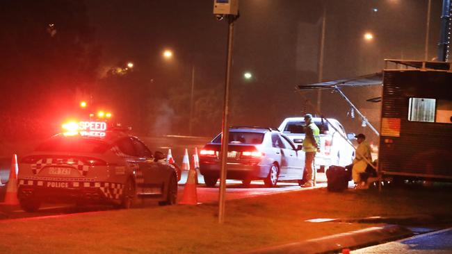 Queensland Police officers with the assistance from the ADF stopping traffic into Queensland for checks at 1am on Saturday morning. Picture: Scott Powick.