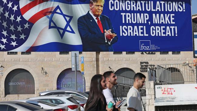 Israelis walk past a billboard congratulating Donald Trump, in Jerusalem. Picture: AFP.