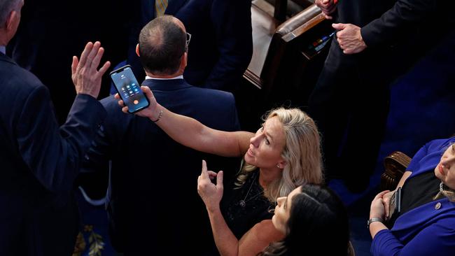 Matt Rosendale refuses to talk with former President Donald Trump on a phone being offered by Marjorie Taylor Greene during the last moments of a contentious debate on the fourth day of voting for a new Speaker of the House. Picture: AFP