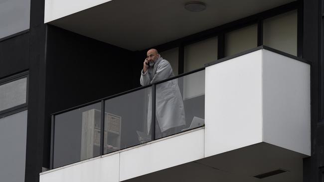 A resident at the Ariele Apartments speaks on the phone while in quarantine. Picture: Andrew Henshaw