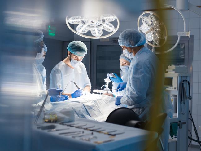 Blurred shot of group of professional surgeons at work in operating room. Emergency case, surgery, medical technology, health care cancer and disease treatment concept