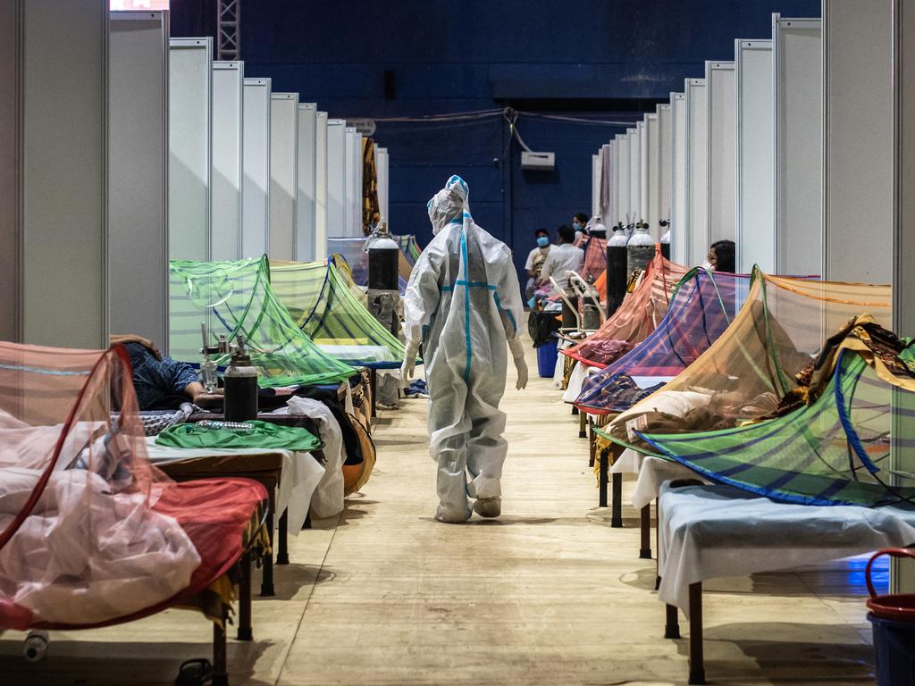 A medical worker in PPE observes patients who have been infected by COVID-19 inside a makeshift facility in a sports stadium in New Delhi. Picture: Getty Images/Getty Images