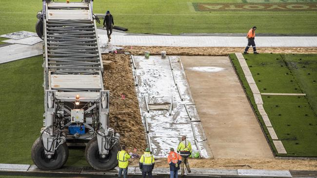 MCG groundsmen install the 10 drop-in cricket pitches. Picture: Jason Edwards