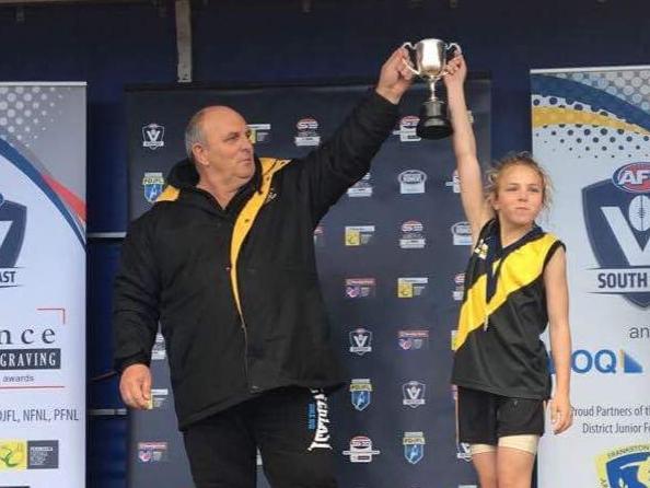 Seaford junior footy coach Mal Lehner and daughter Dakota hold up the premiership cup in 2017.