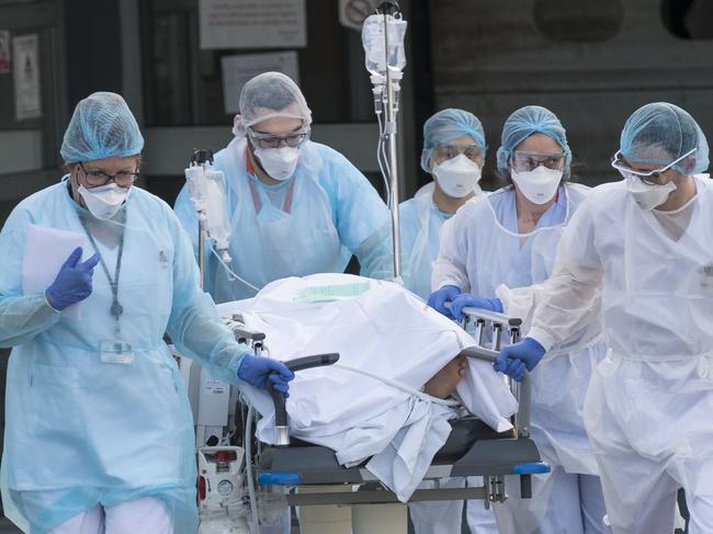 TOPSHOT - Medical staff push a patient on a gurney to a waiting medical helicopter at the Emile Muller hospital in Mulhouse, eastern France, to be evacuated on another hospital on March 17, 2020, amid the outbreak of the new Coronavirus, COVID-19. - A strict lock down requiring most people in France to remain at home came into effect at midday on March 17, 2020, prohibiting all but essential outings in a bid to curb the coronavirus spread. The country has reported 148 deaths from the virus, a number that health experts warn could soar in the coming days, seriously straining the hospital system. (Photo by SEBASTIEN BOZON / AFP)