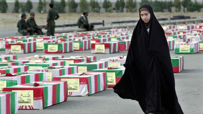 24/07/2002. A veiled Iranian woman passes coffins of soldiers, draped in Iran's national flag, who were killed during the Iran-Iraq war of 1980-88, during a ceremony at Mehrabad International airport in Tehran, Iran. (AP Photo/Hasan Sarbakhshian)