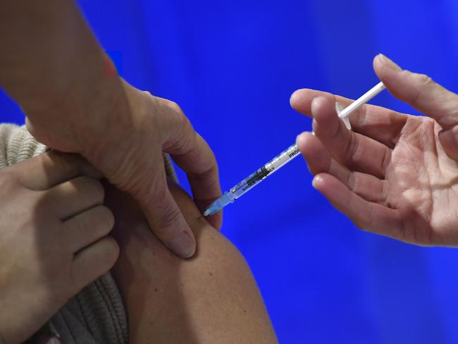 CARDIFF, WALES - DECEMBER 08: A woman receives an injection of the Pfizer-BioNTech Covid-19 vaccine at a health centre on the first day of the largest immunisation programme in the UK's history on December 8, 2020 in Cardiff, United Kingdom.  Wales joined the other UK nations in rolling out the covid-19 vaccine on Tuesday, a rare moment of coordination after months of disjointedness in the four nations' pandemic response. Wales introduced a 17-day "firebreak" lockdown in October and November to suppress the surge in covid-19 cases, but infections have continued to rise. (Photo by Justin Tallis - Pool / Getty Images)