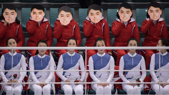 TOPSHOT - A photo taken on February 10, 2018 shows North Korean cheerleaders wearing masks as they perform during the women's preliminary round ice hockey match between the unified Korea team and Switzerland at the Pyeongchang 2018 Winter Olympics, at the Gangneung Ice Arena in Gangneung. According to Yonhap, South Korea's unification ministry has denied reports that the masks featured the image of North Korea's late founding leader Kim Il-sung. The masks were worn as the cheerleaders sang 'Whistle', a North Korean song whose lyrics are about a man's unrequited love for a female neighbor. / AFP PHOTO / Ed JONES