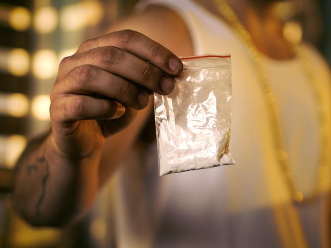 Brutal Drug Dealer Wearing Sleeveless Shirt and Gold Chain Holds and Offers Sample Bag Full of Drugs. He Lives in the Abandoned Building with Boarded Up Windows.