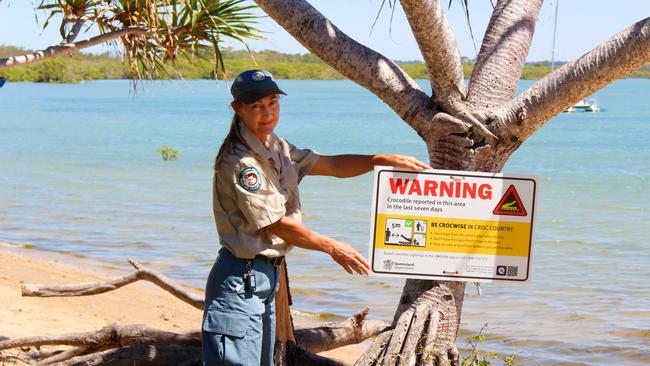 Senior Wildlife Officer Tina Ball with a croc warning sign at Point Vernon, Hervey Bay, where searches for a crocodile were carried out in 2020.