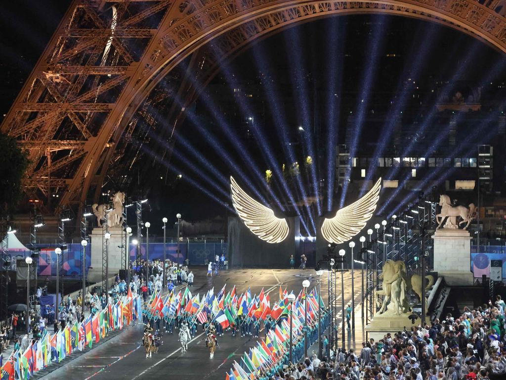 Floriane Issert, a Gendarmerie non-commissioned officer of the National Gendarmerie, carries the Olympic flag as she rides on the Iena bridge during the opening ceremony of the Paris 2024 Olympic Games in Paris on July 26, 2024, as the Eiffel Tower is seen in the background. (Photo by Ludovic MARIN / POOL / AFP)