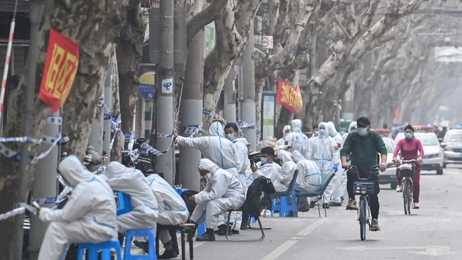 Workers are seen wearing protective clothes next to some lockdown areas after the detection of new cases of Covid-19 in Shanghai. Picture: AFP.