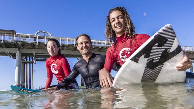 Matthew Barber from Elanora State High School has been named a finalist in this year’s QCT TEACHX Awards for his work connecting students with surfing through the CooeeGC Program. Here he is pictured with CooeeGC students Gemma Rosenvald and Kaya Horn. Photo: Nigel Hallett