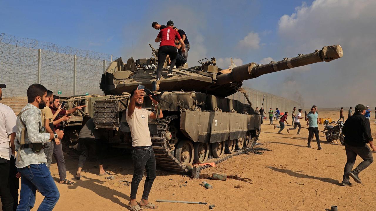 Palestinians take control of an Israeli tank after crossing the border fence with Israel from Khan Yunis in the southern Gaza Strip. Picture: Said Khatib / AFP