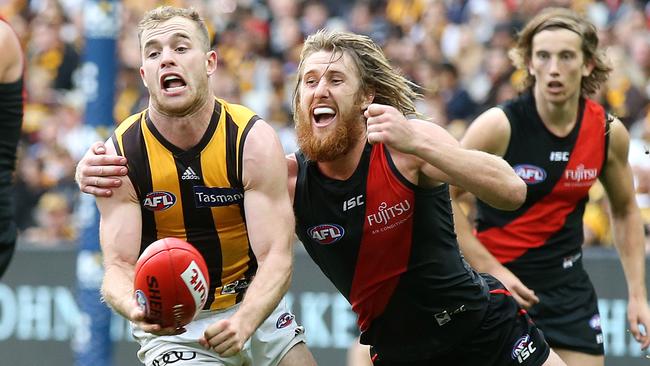 Tom Mitchell handballs as he is tackled by Dyson Heppell. Picture: Michael Klein