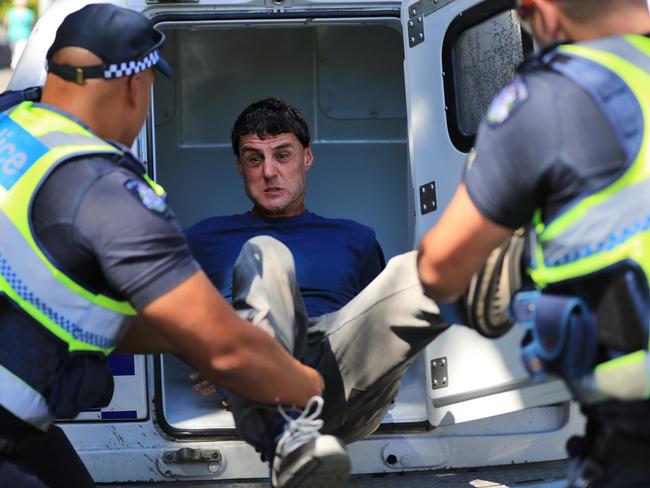 Officers force the man in to the back of a divvy-van after he continues to act violently. Picture: Alex Coppel.