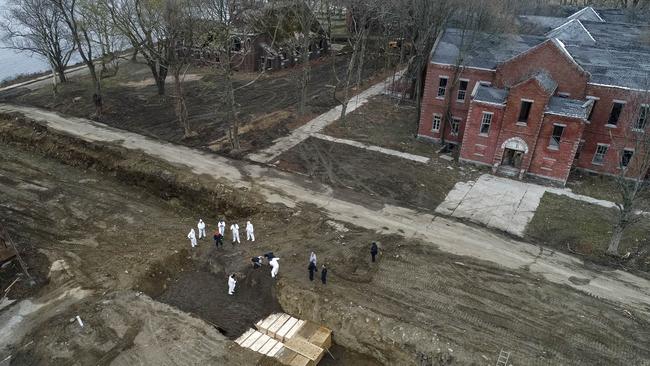 Workers wearing personal protective equipment bury bodies in a trench on Hart Island in the Bronx borough of New York.