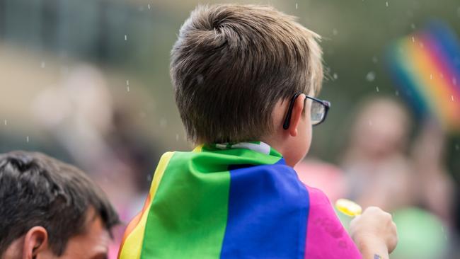 Young child celebrates Pride Parade while wearing bright rainbow flag. Supporting marriage equality and LGBT rights.