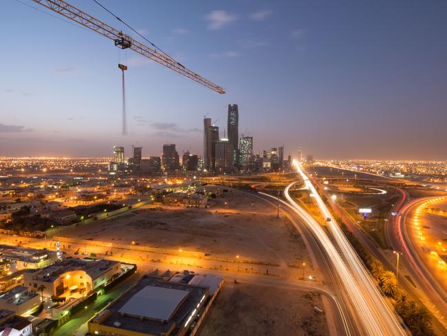 A construction crane sits above an illuminated highway leading past the King Abdullah financial district, center, in Riyadh, Saudi Arabia, on Friday, Jan. 8, 2016. Saudi Arabian stocks led Gulf Arab markets lower after oil extended its slump from the lowest close since 2004. Photographer: Waseem Obaidi/Bloomberg