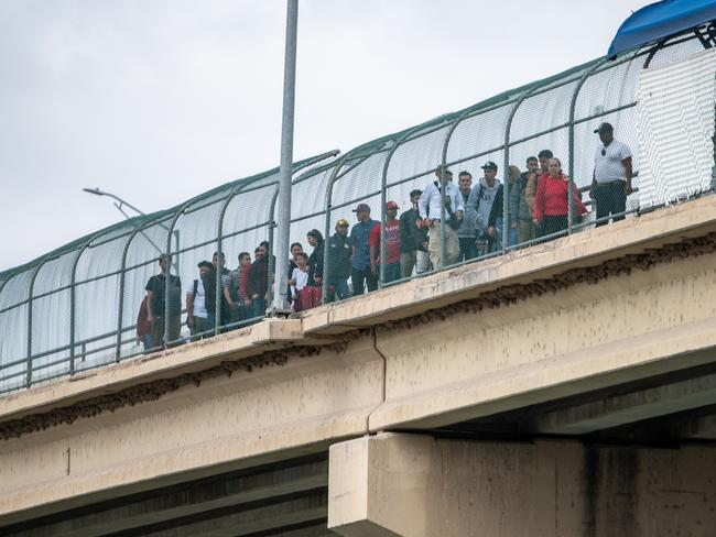 A group of migrants with appointments with Customs and Border Protection wait to be processed on a bridge into Eagle Pass. Picture: Sergio Flores