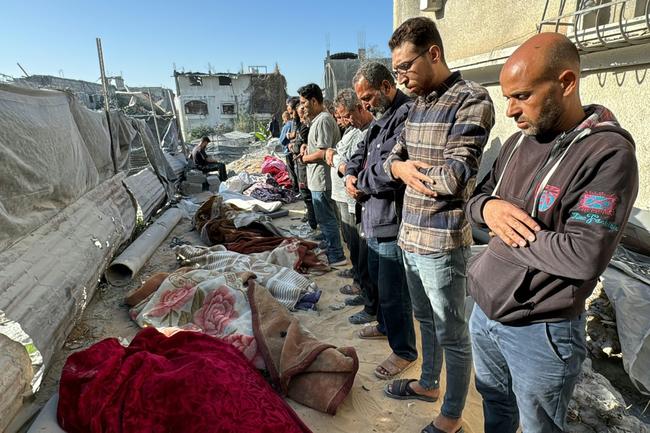 Palestinians pray over bodies of relatives, killed in an overnight Israeli airstrike in Beit Lahia in the northern Gaza Strip