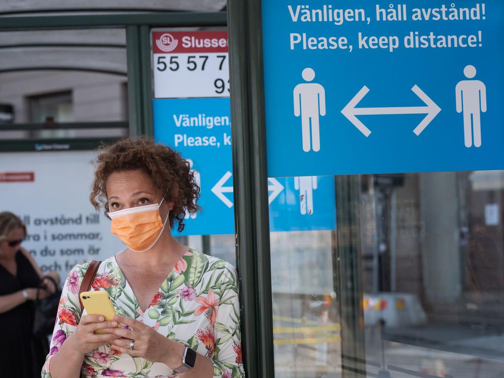 A woman wears a face mask as she waits at a bus stop in Stockholm, Sweden. Picture: Stina Stjernkvist/AFP