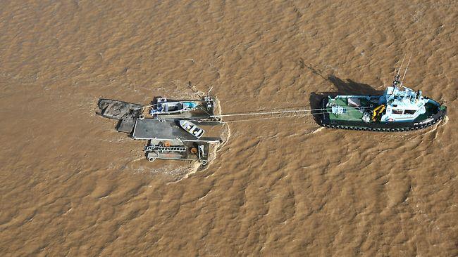 A boat removes debris from the Brisbane River. Picture: Brad Hunter