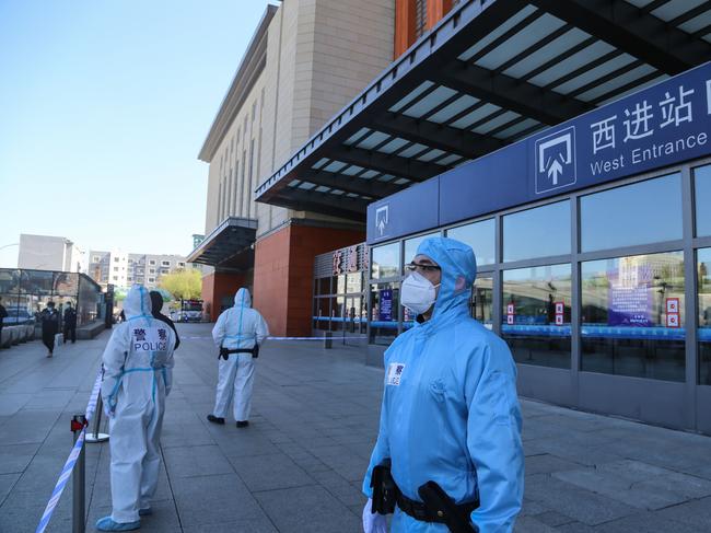 Police officers clad in protective suits stand guard outside Jilin city's railway station in China's Jilin Province. Picture: AFP