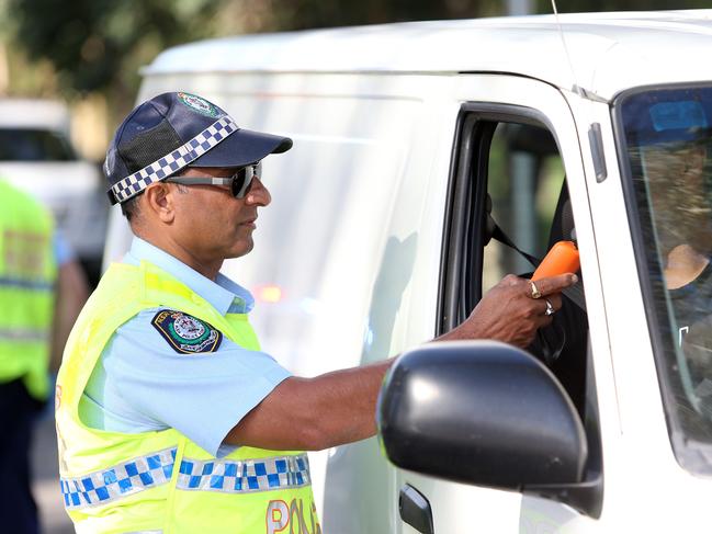 Senior constable Gurmit Bunait conducting breath tests during the operation.Police were conducting Random Breath tests and also Drug tests on Henry Lawson dr in Georges Hall as part of Operation MERRETT on Monday the 26th of March 2018.(AAP IMAGE/Justin Sanson)