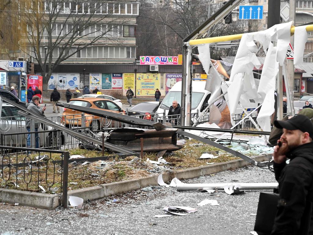 Police and security personnel inspect gather by the remains of a shell landed in a street in Kyiv on February 24, 2022.