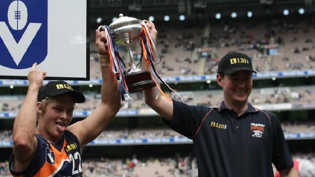 Captain Mitch Farmer holds the premiership cup aloft with Cannons coach David Flood.