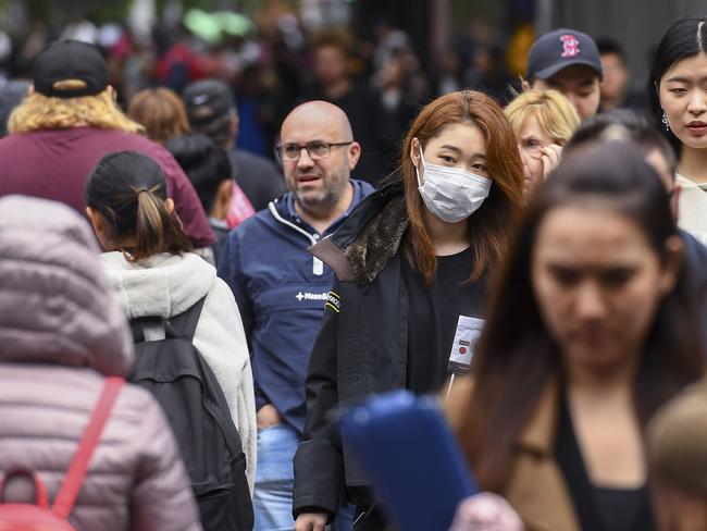 A woman wearing a face mask crosses the street in Melbourne on March 5, 2020. - Over 50 people have been confirmed to have the COVID-19 coronavirus in Australia so far with the latest cases including an eight-month-old baby in Adelaide. (Photo by William WEST / AFP)