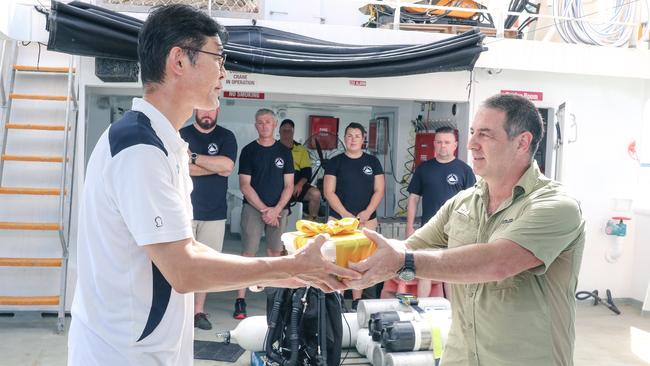 Marine archaeologist David Steinberg presents Takenobu Hamaguchi with sand from the vicinity of the Japanese WWII wreck of I -124 submarine as a dive expedition returns from a Heritage documentation trip. Picture: Glenn Campbell