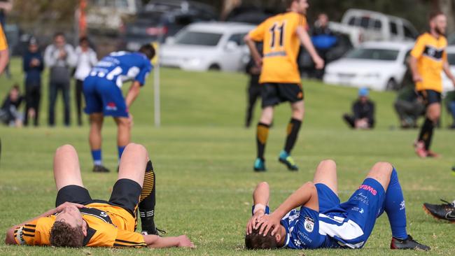 An exhausted Tea Tree Gully and West Adelaide player slump to the ground after the final whistle of their FFA Cup clash – a shock 1-0 win to the Gullies. Picture: Adam Butler