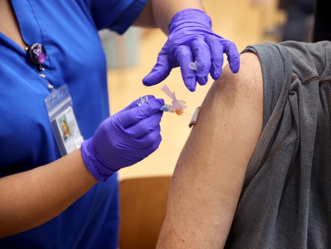 HINES, ILLINOIS - SEPTEMBER 24: Lalain Reyeg administers a COVID-19 booster vaccine and an influenza vaccine to Army veteran Gary Nasakaitis at the Edward Hines Jr. VA Hospital on September 24, 2021 in Hines, Illinois. Today, CDC Director Rochelle Walensky endorsed a booster shot of the Pfizer-BioNTech COVID-19 vaccine for people 65 years and older, those with underlying medical conditions or those who work in high-risk situations.   Scott Olson/Getty Images/AFP == FOR NEWSPAPERS, INTERNET, TELCOS & TELEVISION USE ONLY ==