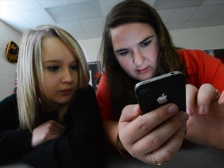 Teenage students use an iPhone in class