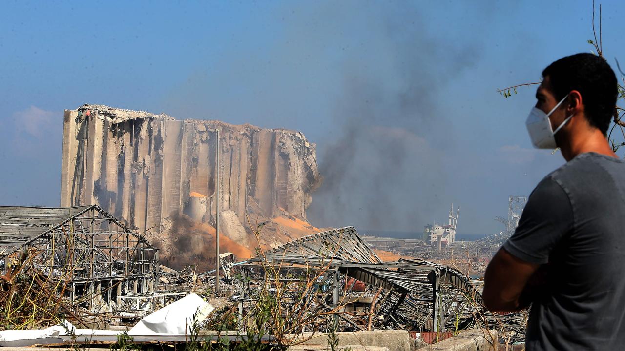 A man wearing a protective mask against the coronavirus stands across the road from the damaged grain silos. Picture: AFP