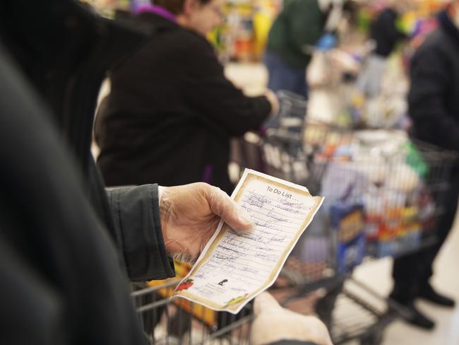 Larry Eleoff, 70, left, looks over his list while waiting in the checkout line at a Stop & Shop supermarket during hours open daily only for seniors Thursday, March 19, 2020, in North Providence, R.I. Eleoff was able to get most of the items on his list. This week grocery store chains and other retailers began offering special shopping hours for seniors and other groups considered the most vulnerable to the new coronavirus. (AP Photo/David Goldman)