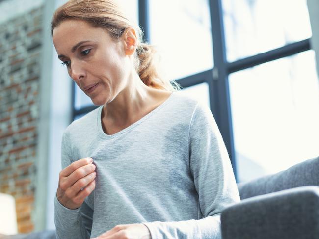 Gradual process. Beautiful mature woman touching sweater and having hot flash