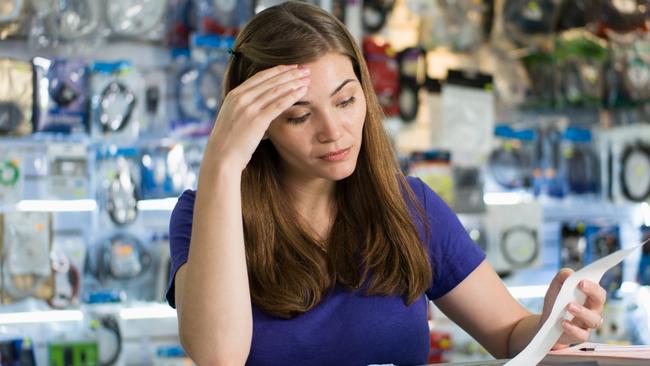 Young white female entrepreneur running a small business and working in computer shop, checking bills and invoices with worried expression istock image