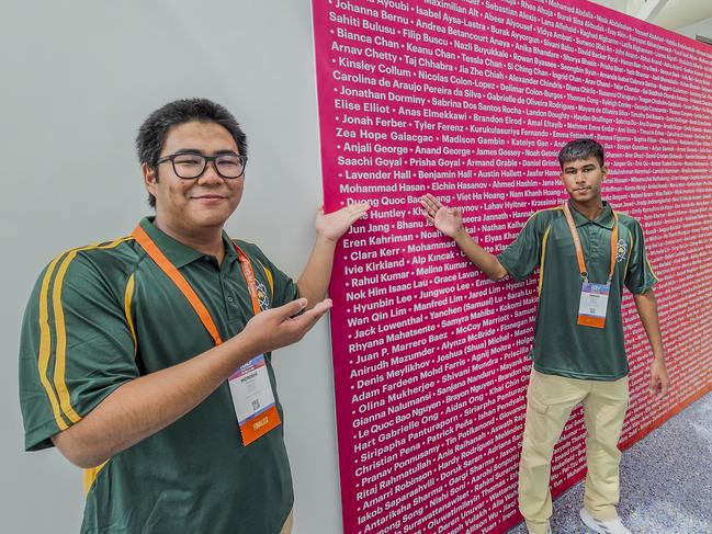 Pothik Vincent Mondol (right) and Monishi Rangchak Tripura (left) point to their missing teammate’s name on an event banner.