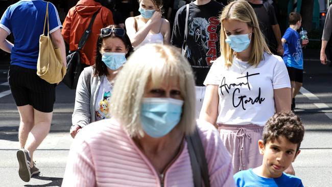 MELBOURNE, AUSTRALIA - DECEMBER 22: People wearing face masks cross Collins Street on December 22, 2021 in Melbourne, Australia. Victoria's COVID-19 case numbers are on the increase across the state, with health authorities also reporting new cases of the Omicron variant. (Photo by Diego Fedele/Getty Images)